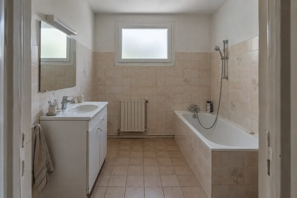 Simulation avant rénovation : salle de bain avec baignoire et ancien carrelage beige.